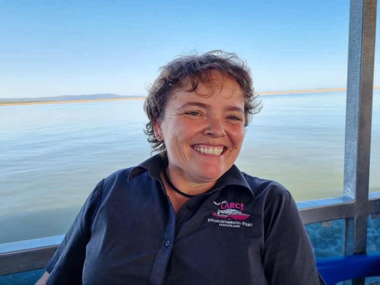 Staff member smiling at camera with ocean in the background.