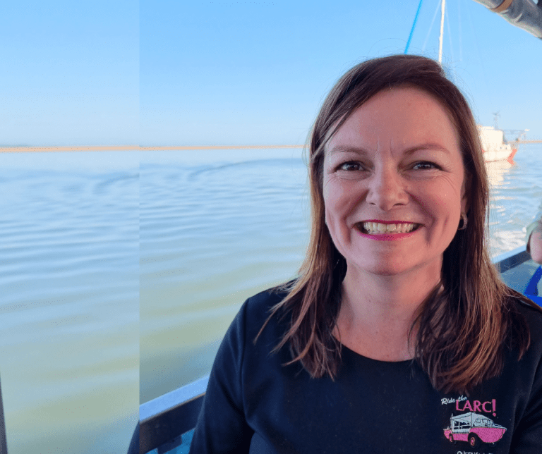 Photo of LARC tour staff member, on the LARC, with the ocean in the background.